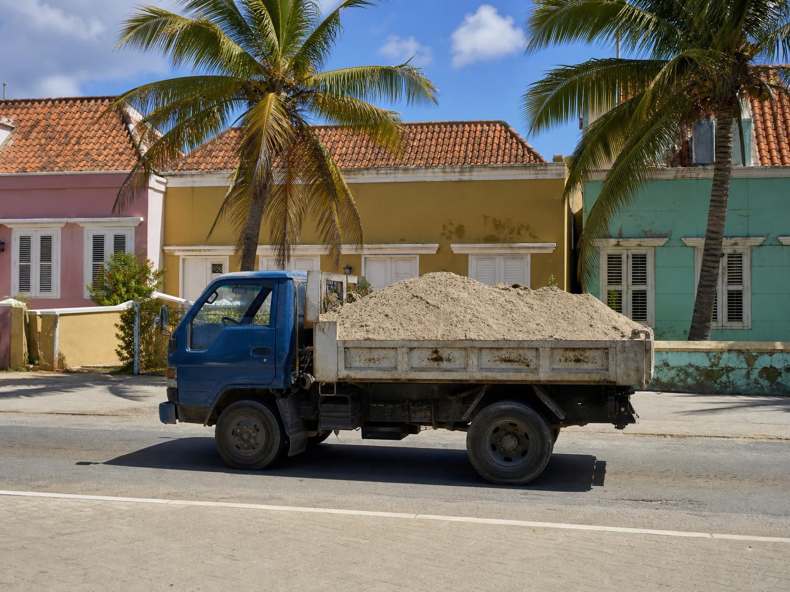 JDS truck loaded with sand parked in front of colourful Curaçao houses